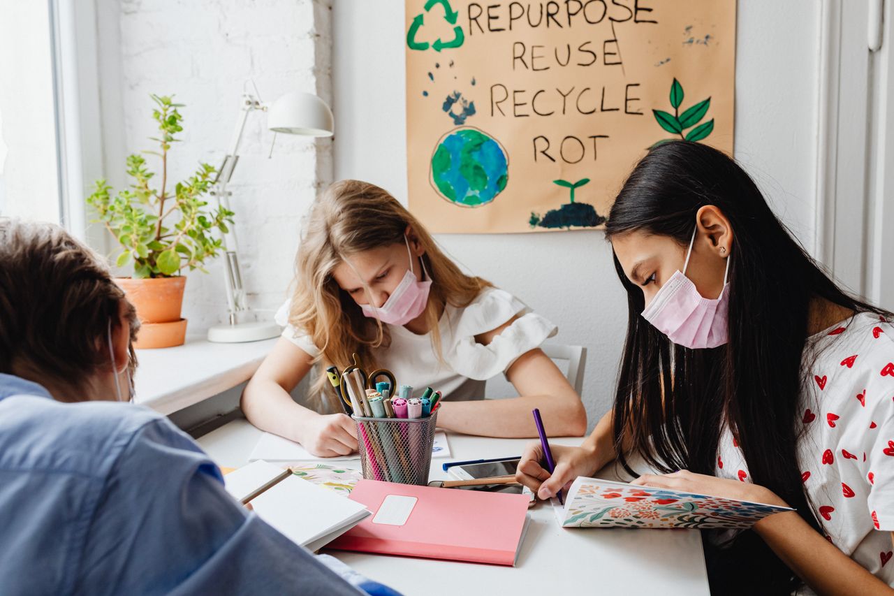 Services Teen girls studying indoors with face masks, emphasizing safety and learning.