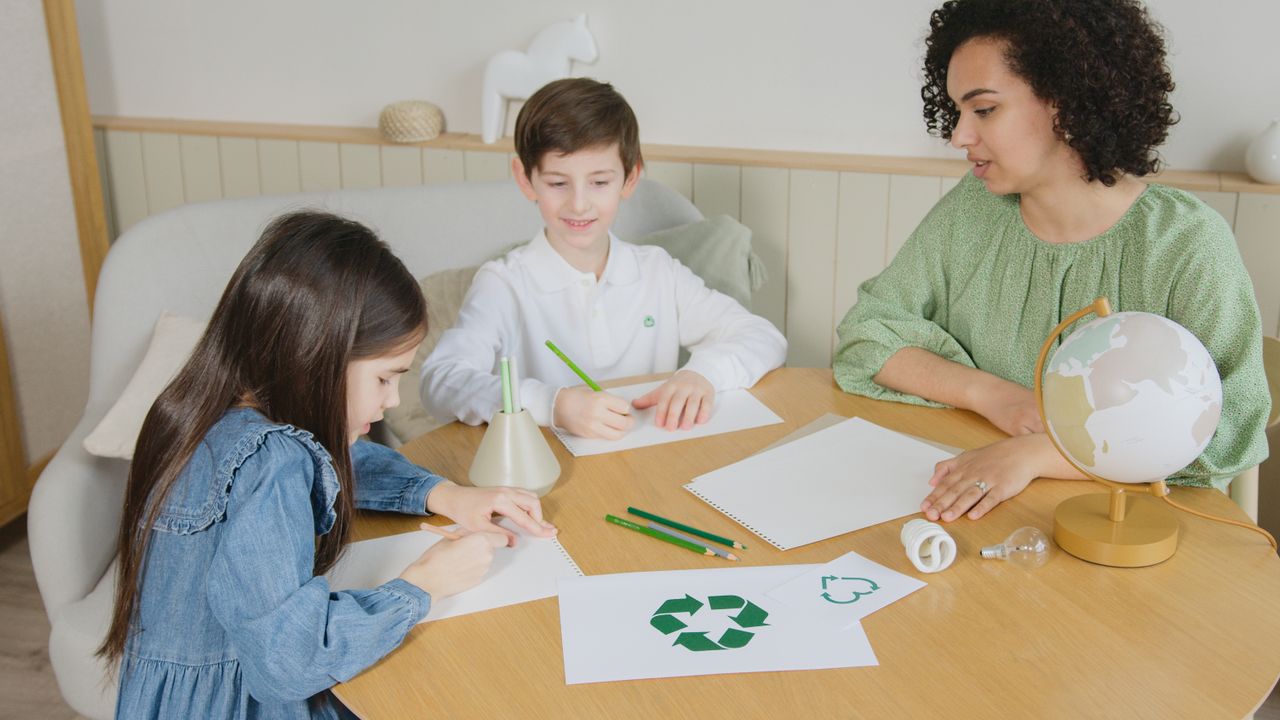 Services Kids with a teacher learning about recycling at a table indoors.
